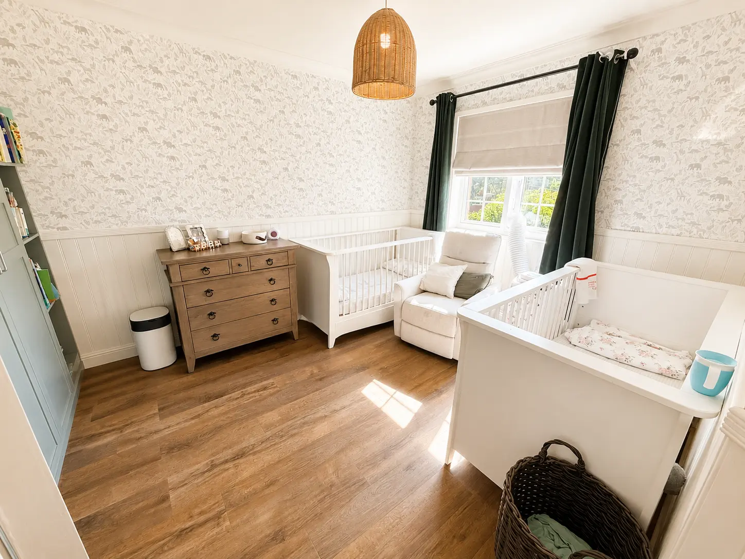 Nursery with two cots, a nursing chair and a chest of drawers
