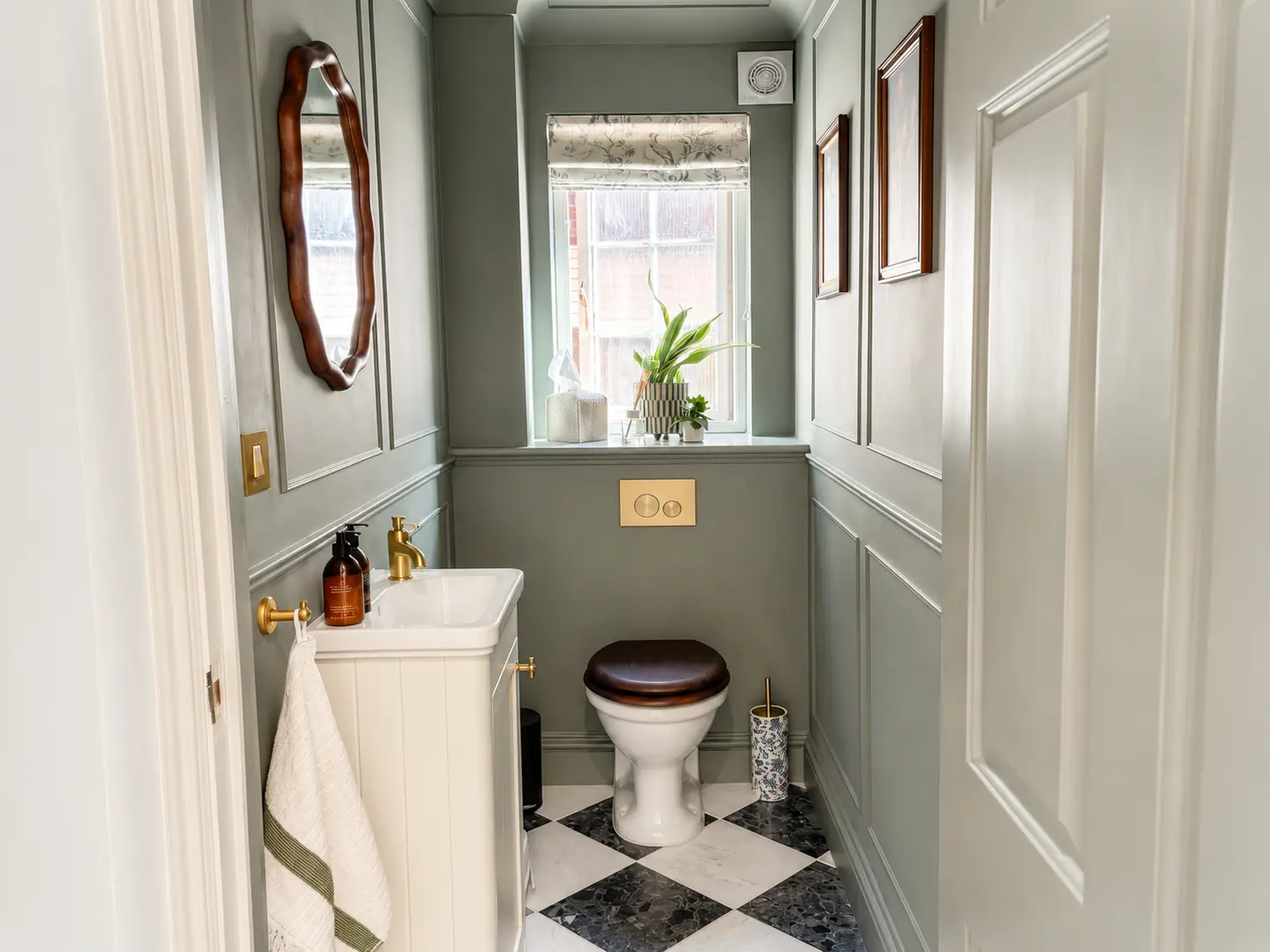 Panelled downstairs WC in soft green with a basin and marble floor