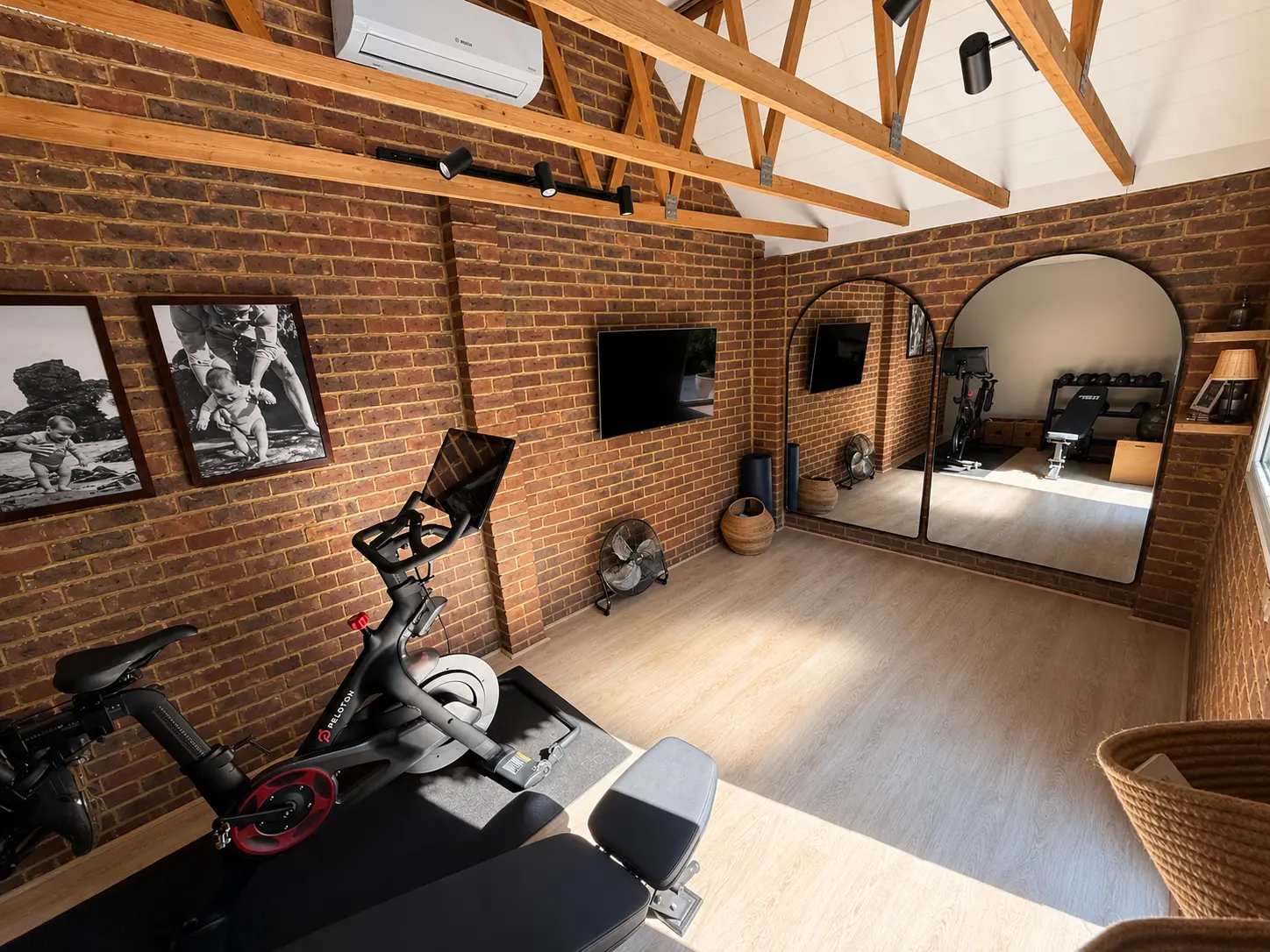 Converted garage gym with exposed brick, bike, weights and mirrors